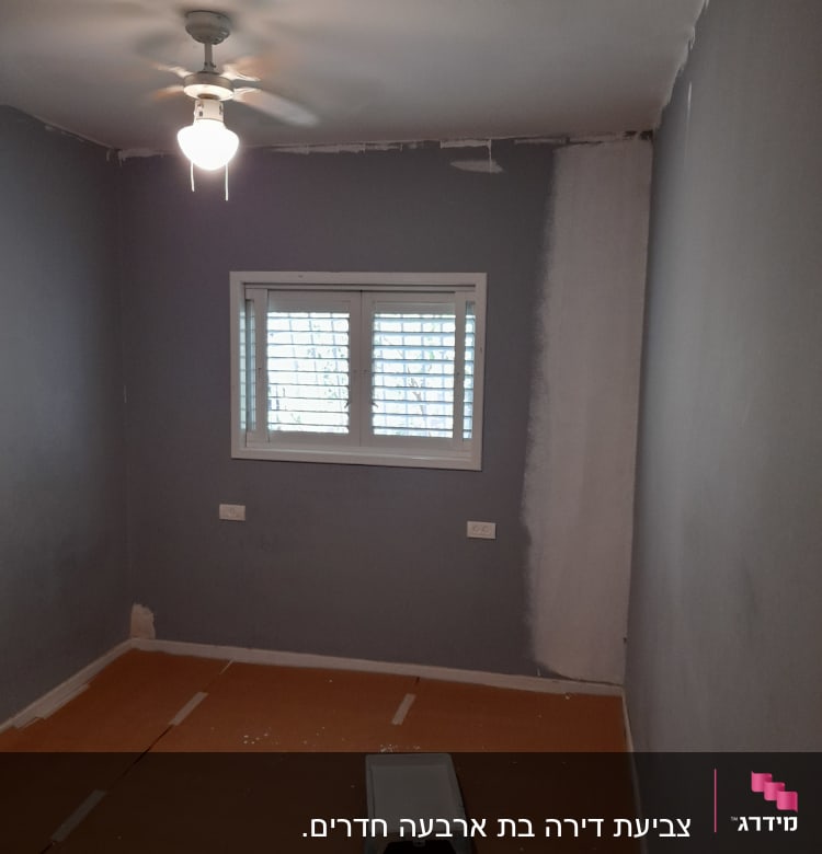 חדר צבוע חלקית עם ציוד צביעה על הרצפה